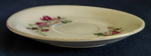 Lade das Bild in den Galerie-Viewer, Weiße Porzellan-Untertasse mit Goldrand und floralem Rosenblumen- und Blättermotiv, dekorativ und elegant gestaltet.